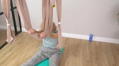 Gözlüklü son sınıf güzeli kadın hamakta egzersiz yapıyor.