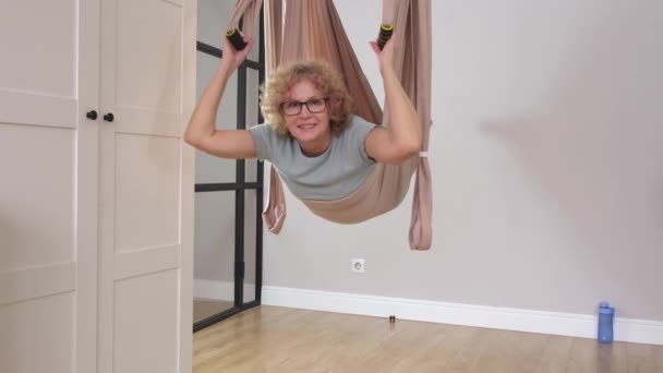 Senior hermosa mujer deportiva con gafas está haciendo ejercicios en la hamaca — Vídeos de Stock