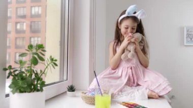 Güzel gülümseyen küçük çocuk Paskalya tavşanı kulakları takıyor ve oyuncak bir hayvan tutuyor.