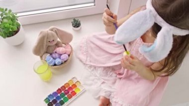 Pembe elbiseli, uzun siyah saçlı, neşeli bir kız.
