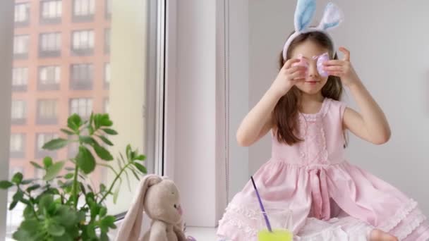 Красива усміхнена дитина носить великодні вуха кролика і тримає яйця — стокове відео