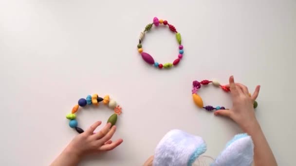 Pohled shora na dětské ruce si hraje s barevnými věnci a vejci z korálků — Stock video