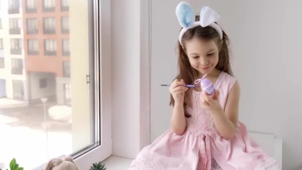 Hermoso niño sonriente está usando orejas de conejo de Pascua y sosteniendo un pincel — Vídeos de Stock
