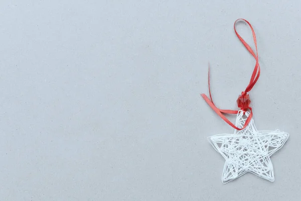 Gwiazdka wykonana z białych nici z czerwoną wstążką po prawej stronie na jasnym, czystym tle. Świąteczna kartka. Nowy rok dekoracji. Widok z góry — Zdjęcie stockowe