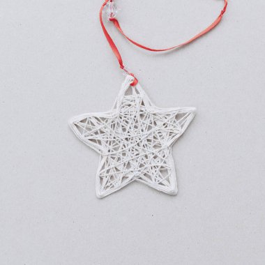 Kırmızı kurdeleli ipliklerden yapılmış beyaz bir yıldız ışık arka planında yatıyor. Üst Manzara. Yeni yıl kartı