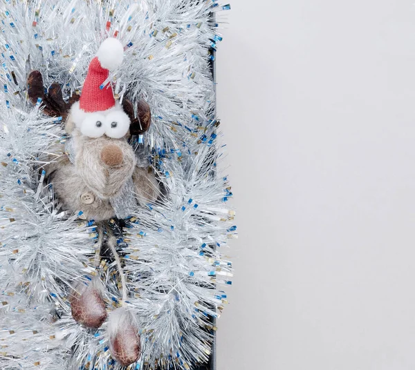 一只长着大眼睛的有趣的玩具鹿躺在银白色的金银财宝里.圣诞装饰。顶部视图 — 图库照片