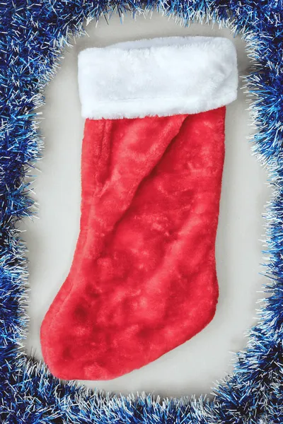 ブルーのティンセルに囲まれたクリスマスプレゼントのための赤と白の靴下。最上階だ。年賀状 — ストック写真