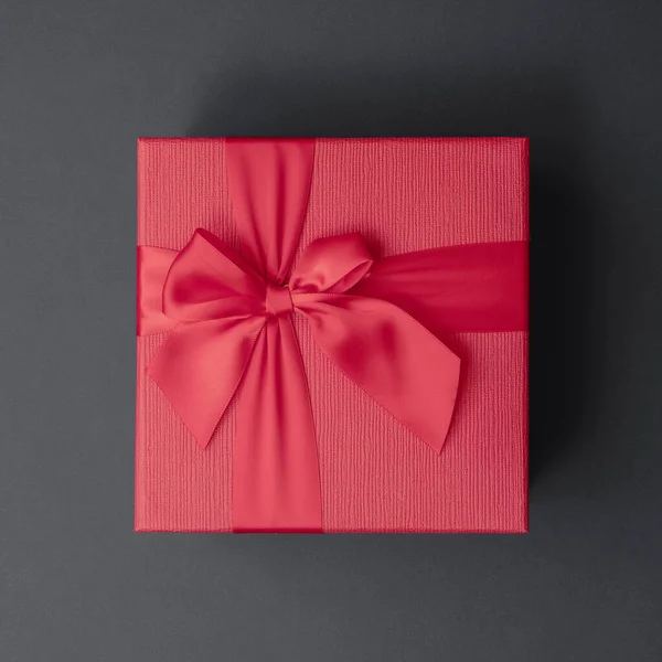 Rode geschenkdoos met strikje op een donkergrijze achtergrond. Vierkant formaat. wenskaart — Stockfoto