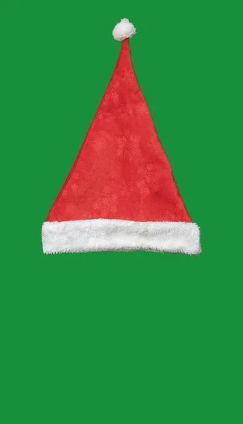 Czerwony aksamitny kapelusz Świętego Mikołaja na zielonym tle. Widok z góry — Zdjęcie stockowe