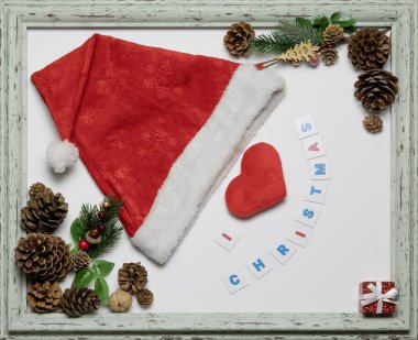 Kırmızı başlık ve kalp, içinde Noel yazıtları ve eşyalar olan bir çerçeve. Noel temalı kart. Düzen bileşimi