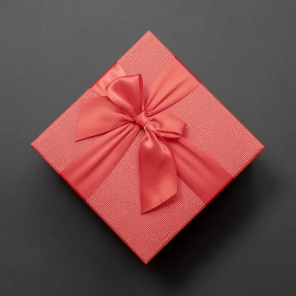 Rode doos met een strik op een donkergrijze achtergrond. Bovenaanzicht. — Stockfoto