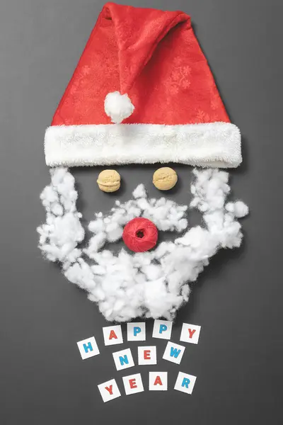 Komposition mit Santas Hut, Walnüssen, einem Faden und Faserfüllung. Lustiges Weihnachtsmann-Gesicht. Neujahrskarte — Stockfoto