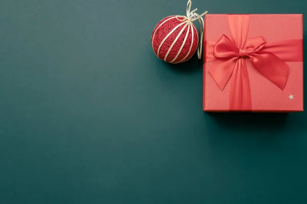 Cadeau rode doos met een strik en een handgemaakte kerstbal in de bovenhoek op een donkergrijze achtergrond. Kerstmockup. Bovenaanzicht — Stockfoto
