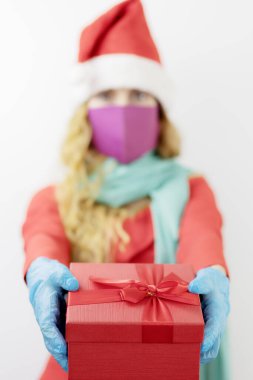 Kırmızı hediye kutusu olan Leydi Noel Baba. Noel için tıbbi steril koruma. Ön plana odaklan.