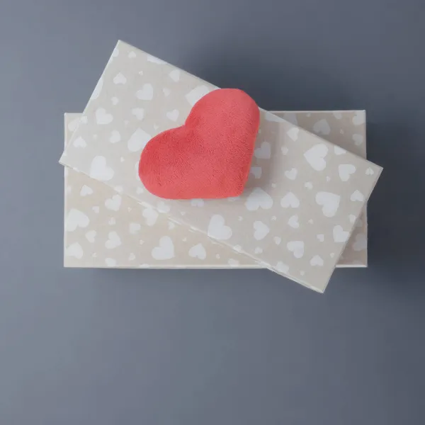 Twee beige geschenkdozen met een hartenpatroon en een rood zacht speeltje van bovenaf op een grijze achtergrond. Bovenaanzicht. Kopieerruimte — Stockfoto