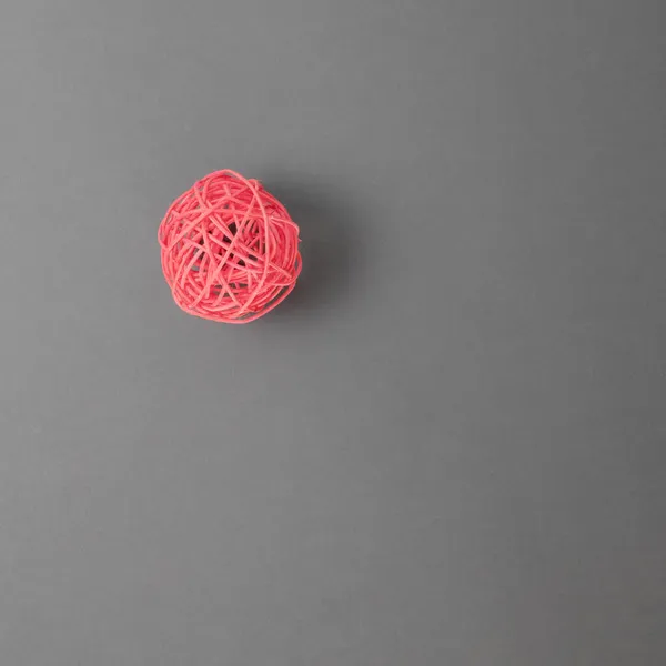 Czerwona pleciona ozdobna piłka na szarym tle. Widok z góry — Zdjęcie stockowe