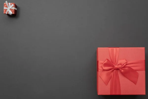 Samenstelling van twee rode geschenkdozen, klein en groot, in tegenovergestelde hoeken op een donkere achtergrond. Wenskaart — Stockfoto