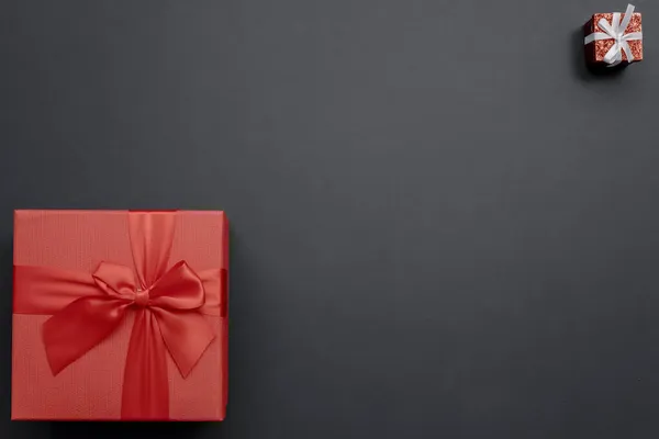Grote en kleine rode geschenkdozen in verschillende hoeken op een donkere achtergrond. Bovenaanzicht — Stockfoto