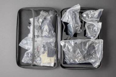 Paketlerin içinde eşyaların olduğu açık gri bir bavul. Kamera ekipmanları. Üst görünüm
