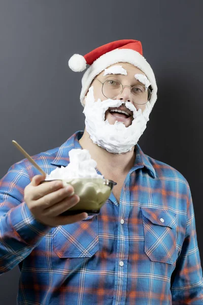 Un Papá Noel disfrazado alegre sostiene un tazón de helado. Deliciosa Navidad. Falso Santa. Feliz cartel de Navidad — Foto de Stock