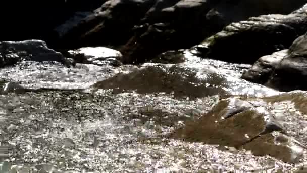 O rio flui sobre as pedras, cintilando ao sol e salpicando. Close-up de vídeo — Vídeo de Stock
