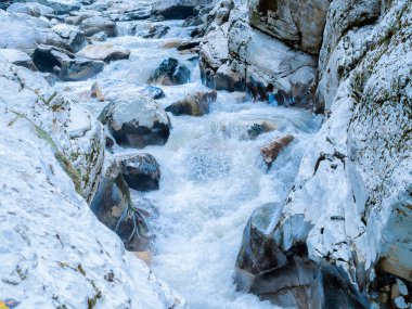 Çalkantılı köpüklü bir nehir kayalık bir geçitte büyük kayaların üzerinden akar. Kanyon beyaz kayaları