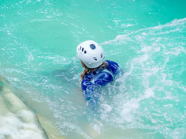La testa nel casco di una nuotatrice sporge fuori dal fiume. Tempo libero. Canyoning. Rafting lungo il fiume — Foto Stock