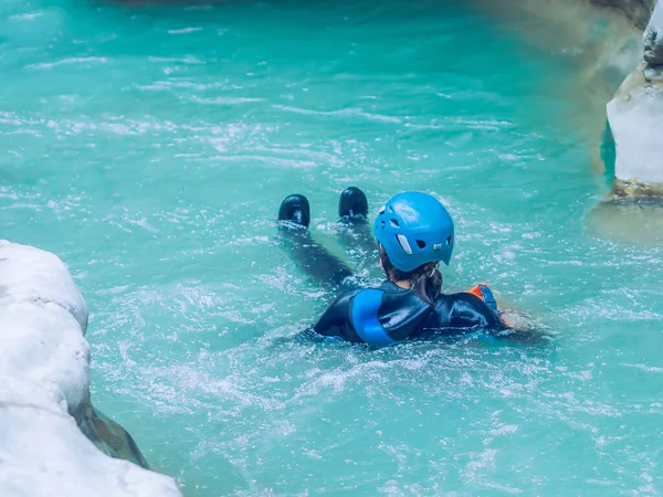 Una donna con una muta e un casco sta facendo rafting in una gola lungo un fiume turchese. Canyoning — Foto Stock