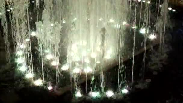 Fragment van de fontein. Waterstralen stijgen, vallen, vliegen in verschillende ritmes met multi-gekleurde verlichting van lampen onder water. — Stockvideo