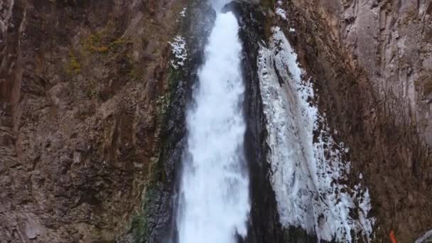 Duży wodospad z zamarzniętym lodem spływa po skale. Kamera nagrywa od dołu do góry i od góry do dołu. Wydaje się, jakby z nieba płynął wodospad. Koncepcja turystyki i rekreacji. — Wideo stockowe