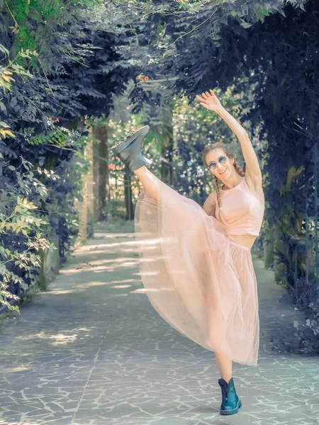 At kuyruklu ve sert ayakkabılı bir kadın yaz parkındaki bir sokakta öne doğru sallanıyor..