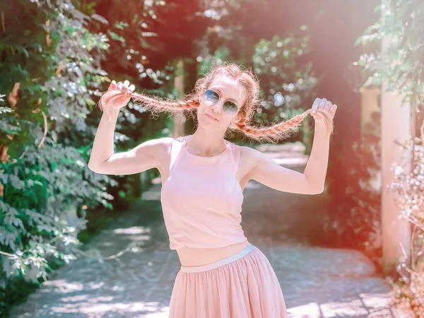 Pani trzyma się za warkocze stojąc w zielonym parku w letni dzień — Zdjęcie stockowe