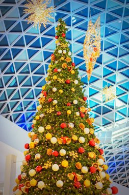 Alışveriş merkezinin vitraylı tavanının altında zarif bir Noel ağacı. Şenlik Dekoru
