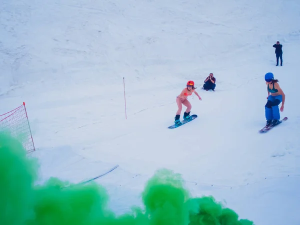 Oroszország, Szocsi 2019.05.11. Egy fürdőruhás lány, egy snowboard és egy síelő lány versenyez a sebességért. Utolsó menet egy zöld füstbombával. Snowboard verseny a vízen. Krasznaja Polyana — Stock Fotó