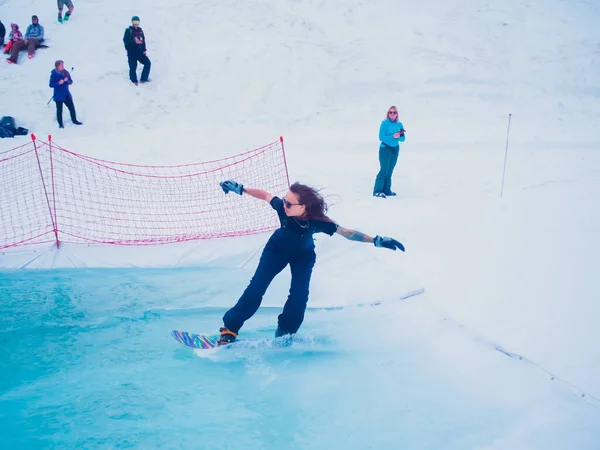 Rússia, Sochi 11.05.2019. Uma menina com uma tatuagem no braço monta um snowboard na água, e o público a observa. Krasnaya Polyana — Fotografia de Stock