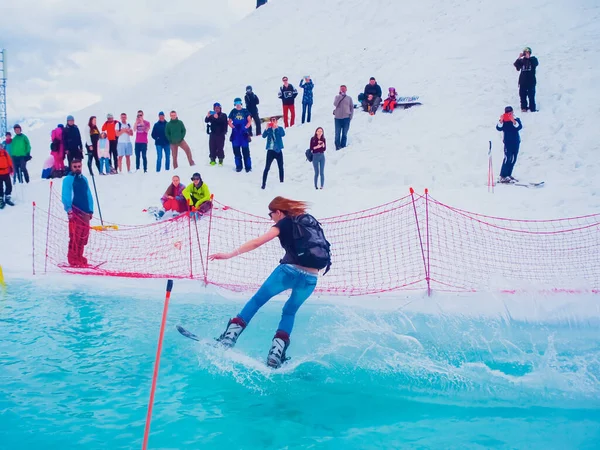 Rusia, Sochi 11.05.2019. Una chica con una mochila y jeans está montando en una tabla de snowboard en el agua y la gente la está observando. Krasnaya Polyana —  Fotos de Stock