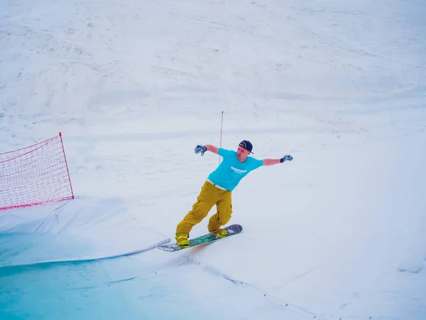 Russland, Sotschi 11.05.2019. Ein Snowboarder mit Schirmmütze und heller Kleidung fliegt auf einem Snowboard ins Wasser. Krasnaja Poljana — Stockfoto