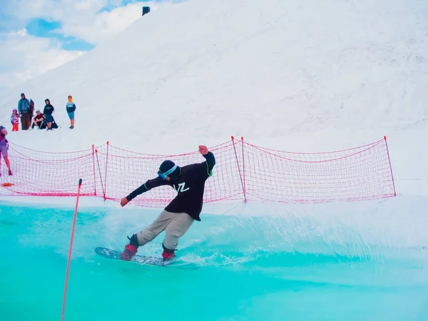 Rússia, Sochi 11.05.2019. Um cavaleiro de alta velocidade atravessa uma piscina de água colorida de bétula. Competição de snowboard na água na estância de esqui Krasnaya Polyana. — Fotografia de Stock