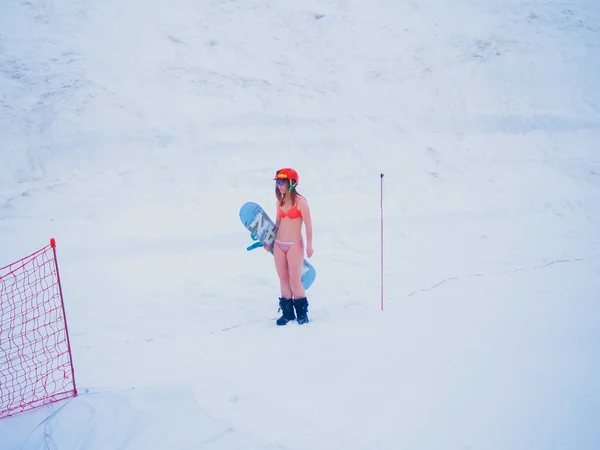 Rússia, Sochi 11.05.2019. Uma menina em um capacete e um maiô laranja fica com um snowboard e assiste a competição. Competições Krasnaya Polyana — Fotografia de Stock