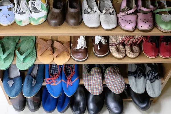 На полке стоят старые детские женские и мужские туфли времен СССР. Ретро-вещи из прошлого. Селективный фокус Лицензионные Стоковые Изображения