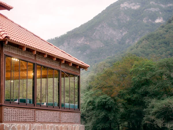 Um fragmento de um café com grandes janelas em pé em um vale de montanha verde em um dia nublado de verão. Café étnico da cozinha caucasiana — Fotografia de Stock