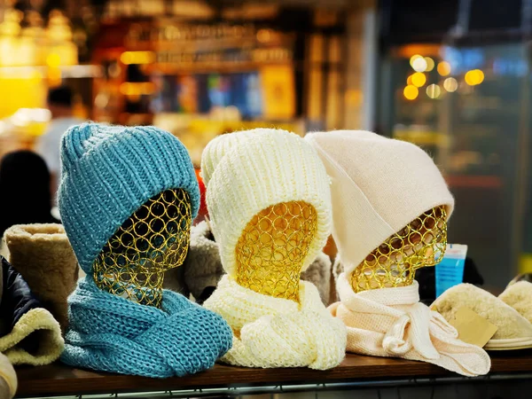 Três manequins de mulheres de padrão dourado em chapéus de inverno tricotados e lenços em uma loja acolhedora. Foco seletivo — Fotografia de Stock