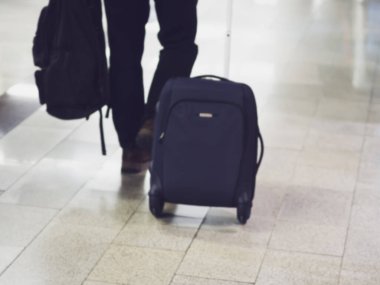 Tekerlekli bavulu ve çantası olan bir yolcu mermer zemine iniyor. Odaklanmamış resim