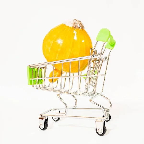 Una cebolla dorada brillante yace en un carrito de supermercado en miniatura sobre ruedas. — Foto de Stock