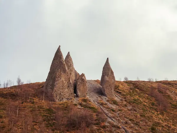 Острые клыкообразные магнетические пирамиды, расположенные в горах под облачным небом. Район у подножия Эльбруса. Остатки древнего извержения вулкана — стоковое фото