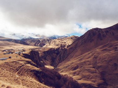 Karlı Elbrus bölgesindeki yüksek sarp Kafkas dağları manzaralı bir vadi. Yoğun bulutlar sönmüş volkanı kapladı.