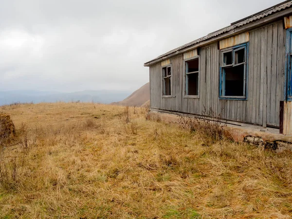 Una vieja casa de madera abandonada en un campo de tierras altas de otoño bajo nubes gruesas colgantes bajas — Foto de Stock