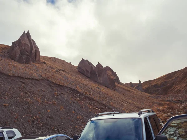 På toppen af bjergene under den overskyede himmel er enorme skarpe stenslag. Magmatiske pyramider. Kaukasisk område Djily-su. Rejsen til foden af Elbrus - Stock-foto