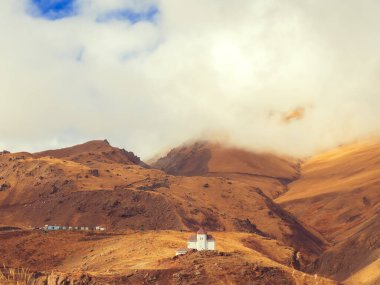 Beyaz bina, dağ zirvelerine doğru inen beyaz bulutlarla Kafkas dağlarının merkezinde yer almaktadır. Kafkasların sonbahar kır manzarası