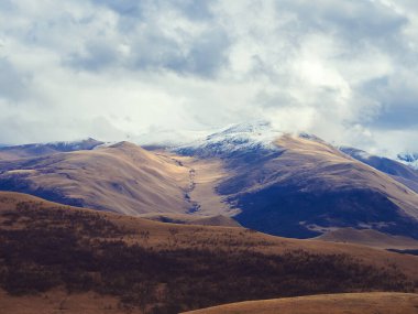 Kahverengi sonbahar Kafkas dağları bulutların altındaki tepelerde karla kaplı. İskoçya 'da keskin bir sıcaklık düşüşü. Alışılmadık bir olay..